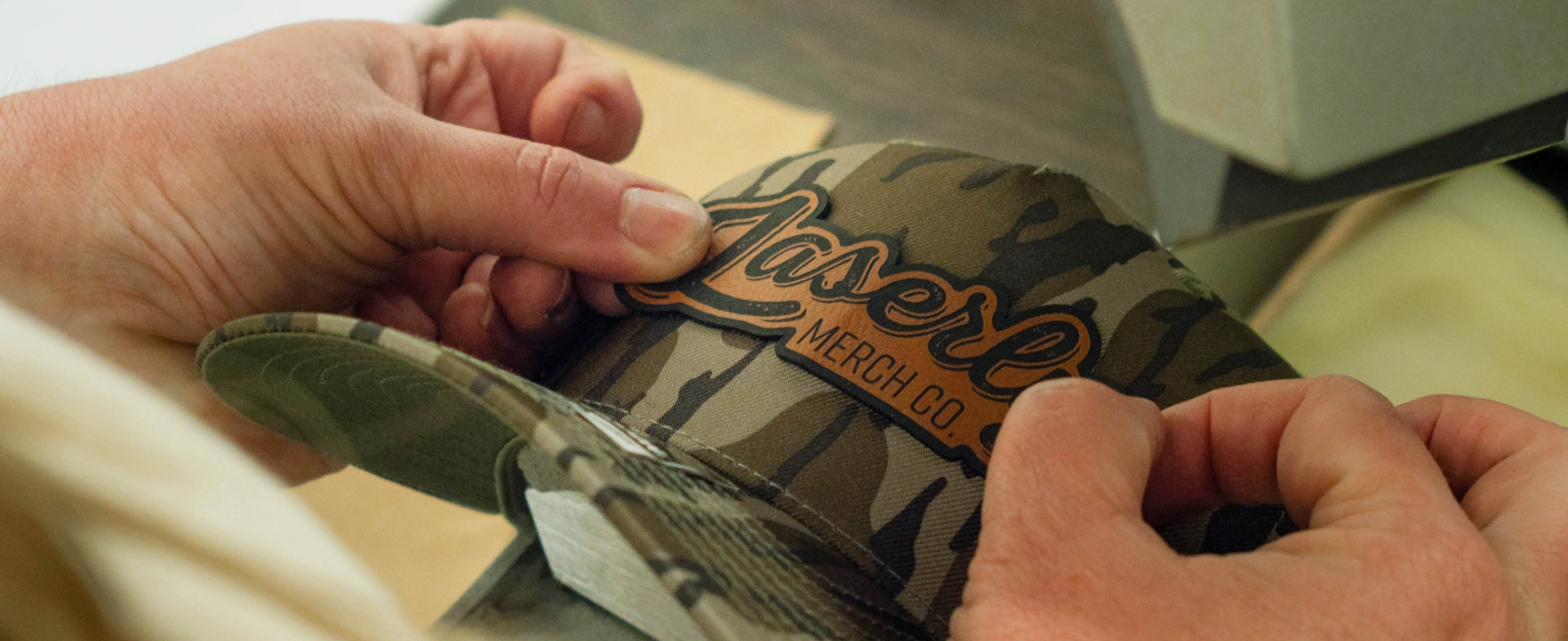 worker putting a custom patch on a hat