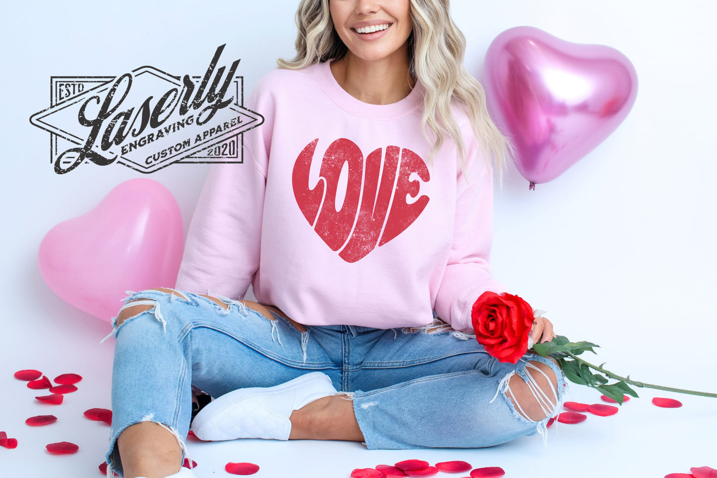 Model wearing a pink sweatshirt with "love" shaped as a heart